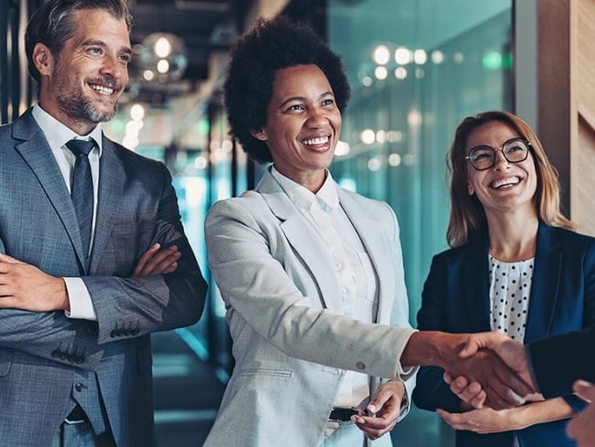 Business professionals shaking hands in a modern office setting, symbolizing agreement and collaboration.