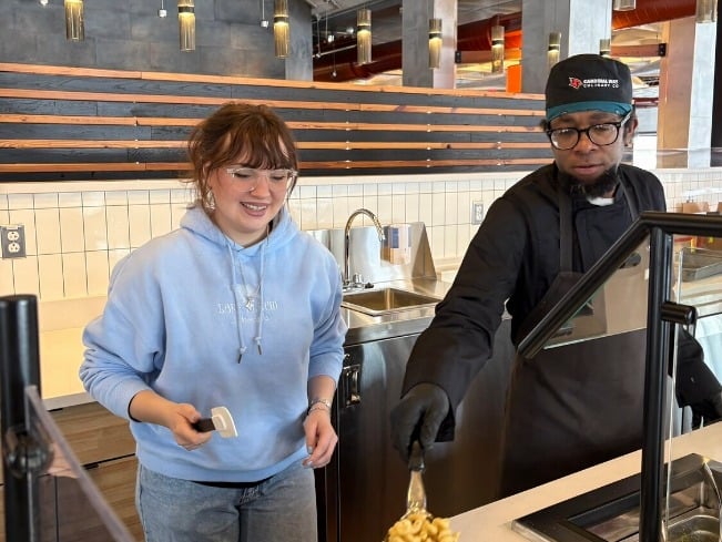 A cook helps a student at the SUNY Plattsburgh UCook station.