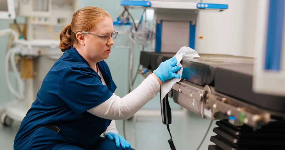 Healthcare professional wearing protective gloves and disinfecting medical equipment as part of hospital infection prevention.