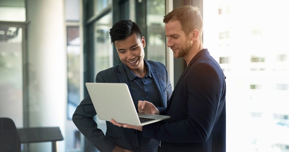 Student intern and supervisor smiling while reviewing content on a laptop, illustrating a positive learning experience in a professional setting.