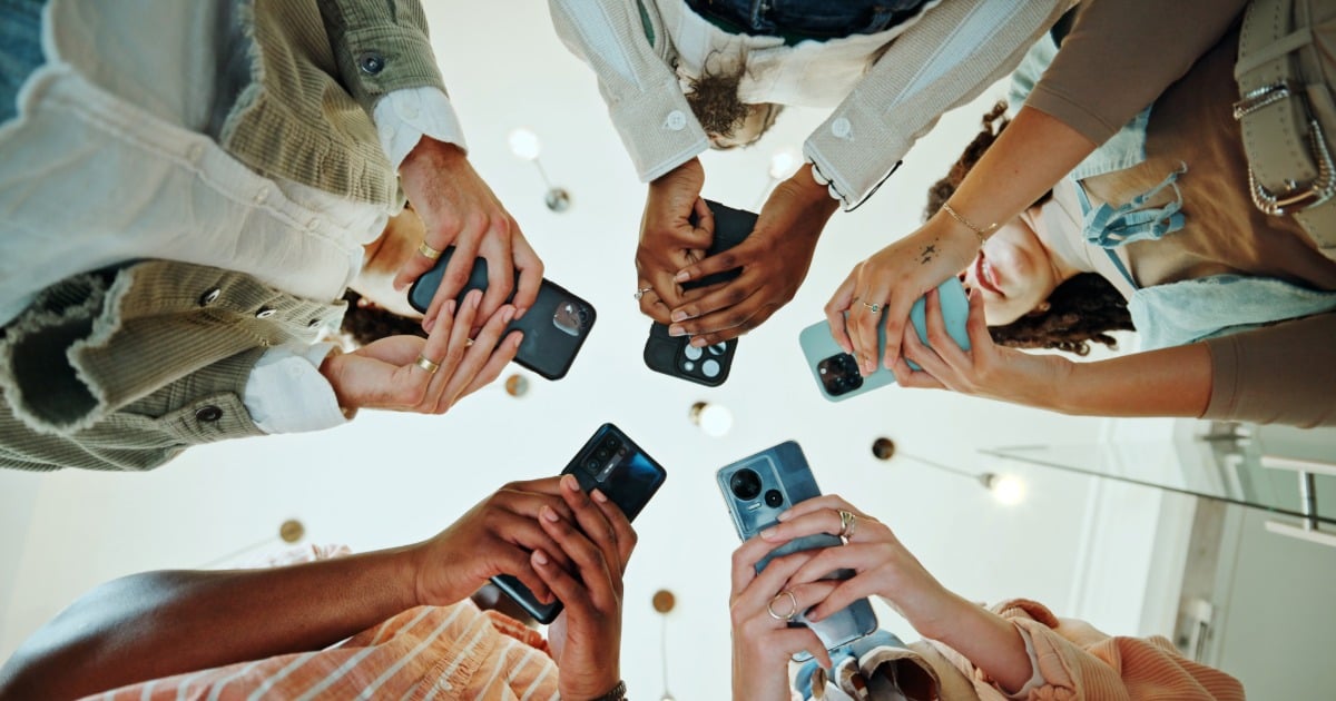 Students gather in a circle using their phones to share ideas and provide insights on campus experiences. 