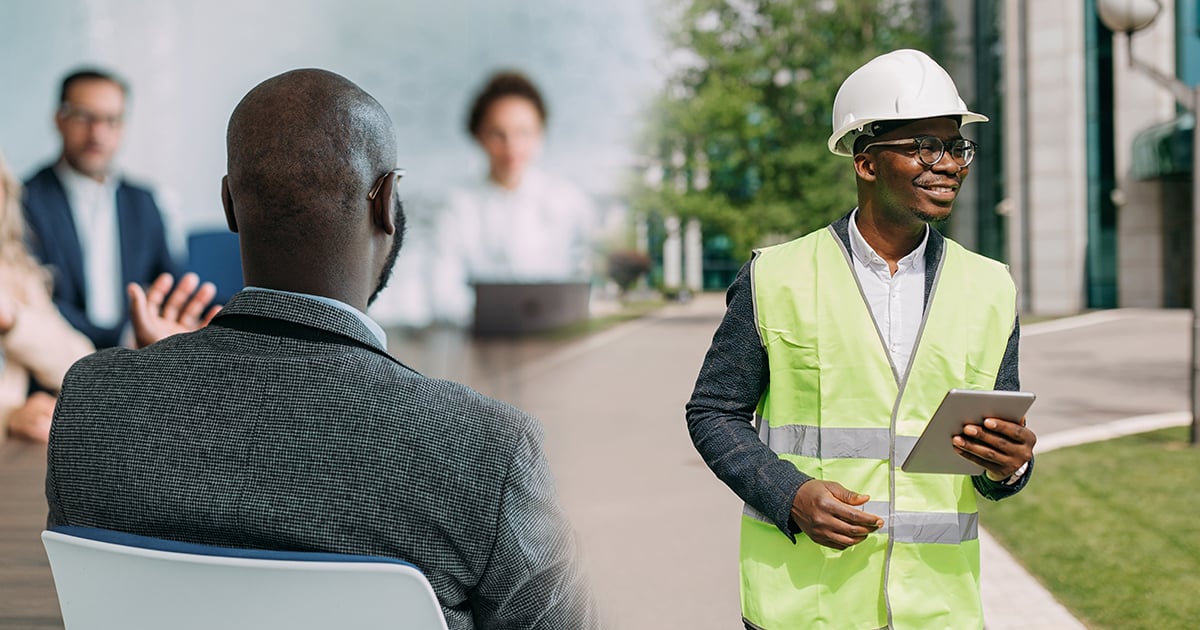 Facilities management professional wearing a safety vest and hard hat while using a tablet outside a commercial building, alongside a business meeting scene highlighting strategy, operations, and workplace management.