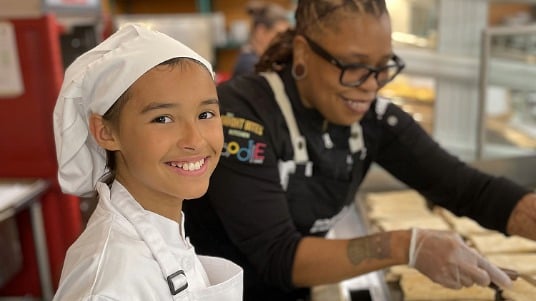 Future Chefs Challenge winner smiling during an in-person kitchen experience with a Sodexo chef.