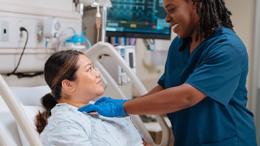 Healthcare support professional assisting a patient in a hospital room, highlighting personalized care, patient comfort, clinical support services, and a positive healthcare experience.
