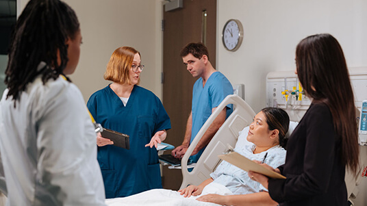 nterdisciplinary care team discussing nutrition and treatment planning with a patient at the bedside.