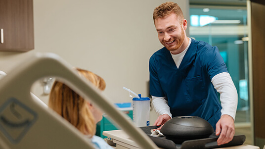 Healthcare professional delivering a meal tray to a patient in a hospital room.