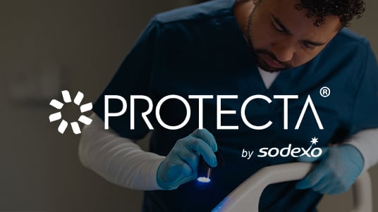 Protecta by Sodexo logo over a healthcare worker in scrubs inspecting equipment with a handheld blue light.