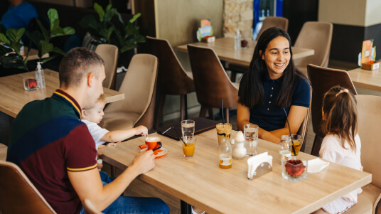 Family sitting at a restaurant table enjoying drinks and food together.