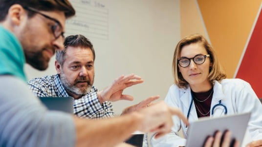 A group of hospital professionals gathered in a meeting room, engaged in discussion.