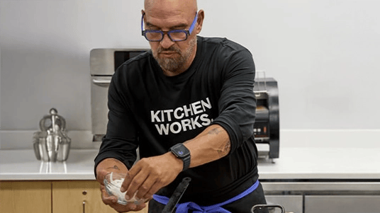Chef Symon adding onions to a pan