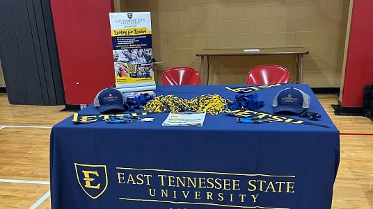 An East Tennessee State University booth decorated with school gear at a college fair.