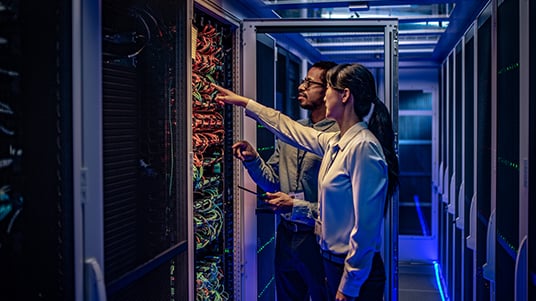 Two workers having a discussion while viewing a server in a data center