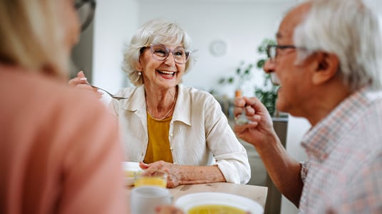 People sitting at a table enjoying bowls of soup and drinks together.