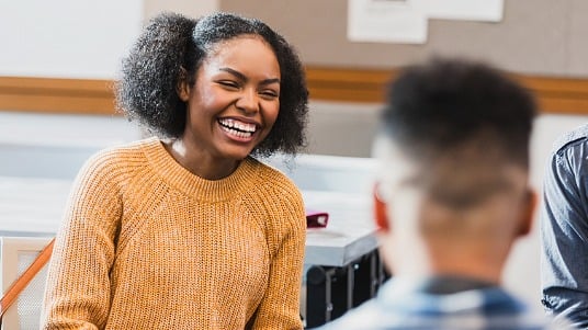 A college student laughing in a classroom, representing positive mental well-being.