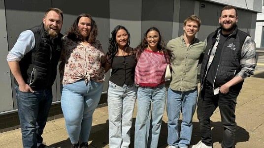 Six Sodexo interns standing close together, smiling at the camera for a group photo. 