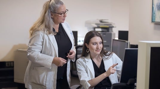 Two dietitians review patient information together at a computer.