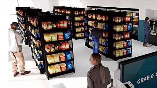 Shoppers browse shelves in a grab-and-go market with packaged snacks and self-service coffee station.