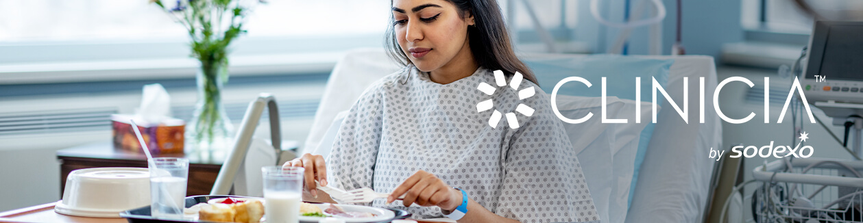 Hospital patient eats meal from tray in bed, with Clinicia by Sodexo logo.