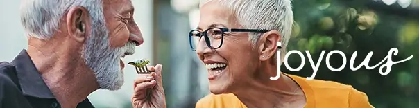 Two elderly individuals, one in glasses and an orange shirt, the other with a white beard.