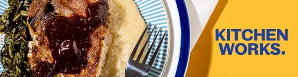 Close-up of a plate with meat in sauce, greens, and mashed potatoes or grits.