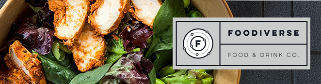 Close-up of a salad topped with sliced breaded chicken, leafy greens, and dried fruit, alongside the Foodiverse Food & Drink Co. logo on a dark background.