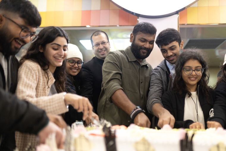 A team of people cheerfully cutting a cake
