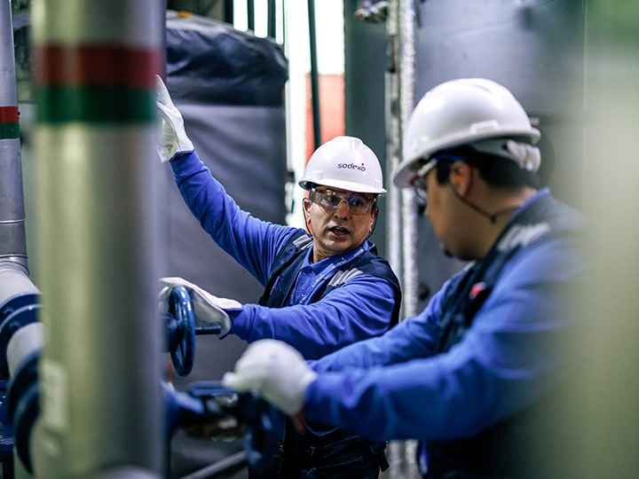 Professionals in blue Sodexo uniforms collaborating on-site