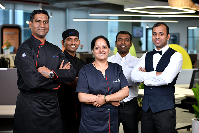 A diverse Sodexo team in uniform and showcasing team spirit.