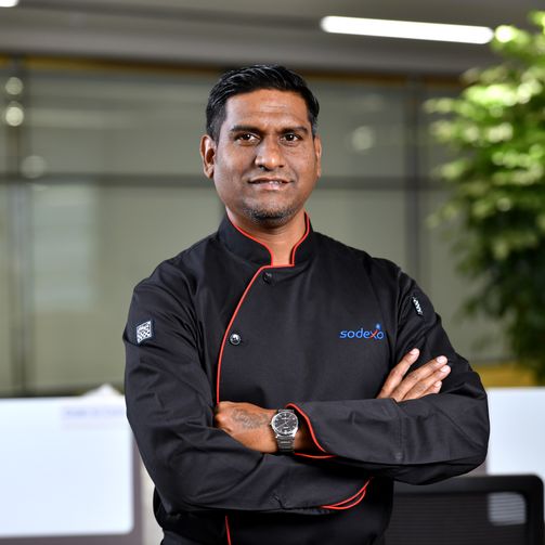 A Sodexo chef in uniform stands confidently