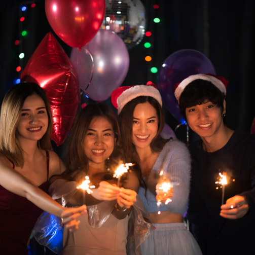 A group of four colleagues with sparklers at an office party. 