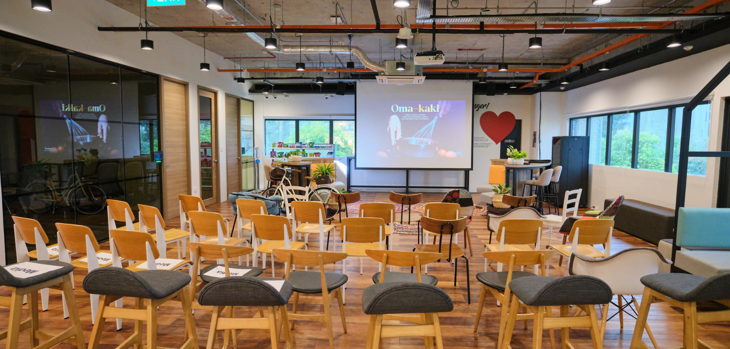 A room set up for a presentation with chairs pointing towards a screen.