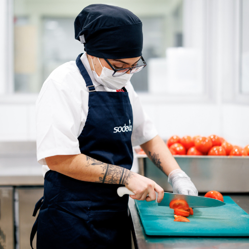 A chef with glasses slices tomatoes