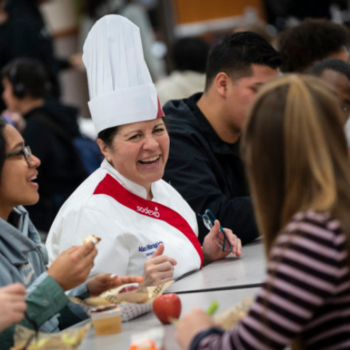 A Sodexo chef laughing at a table surrounded by students