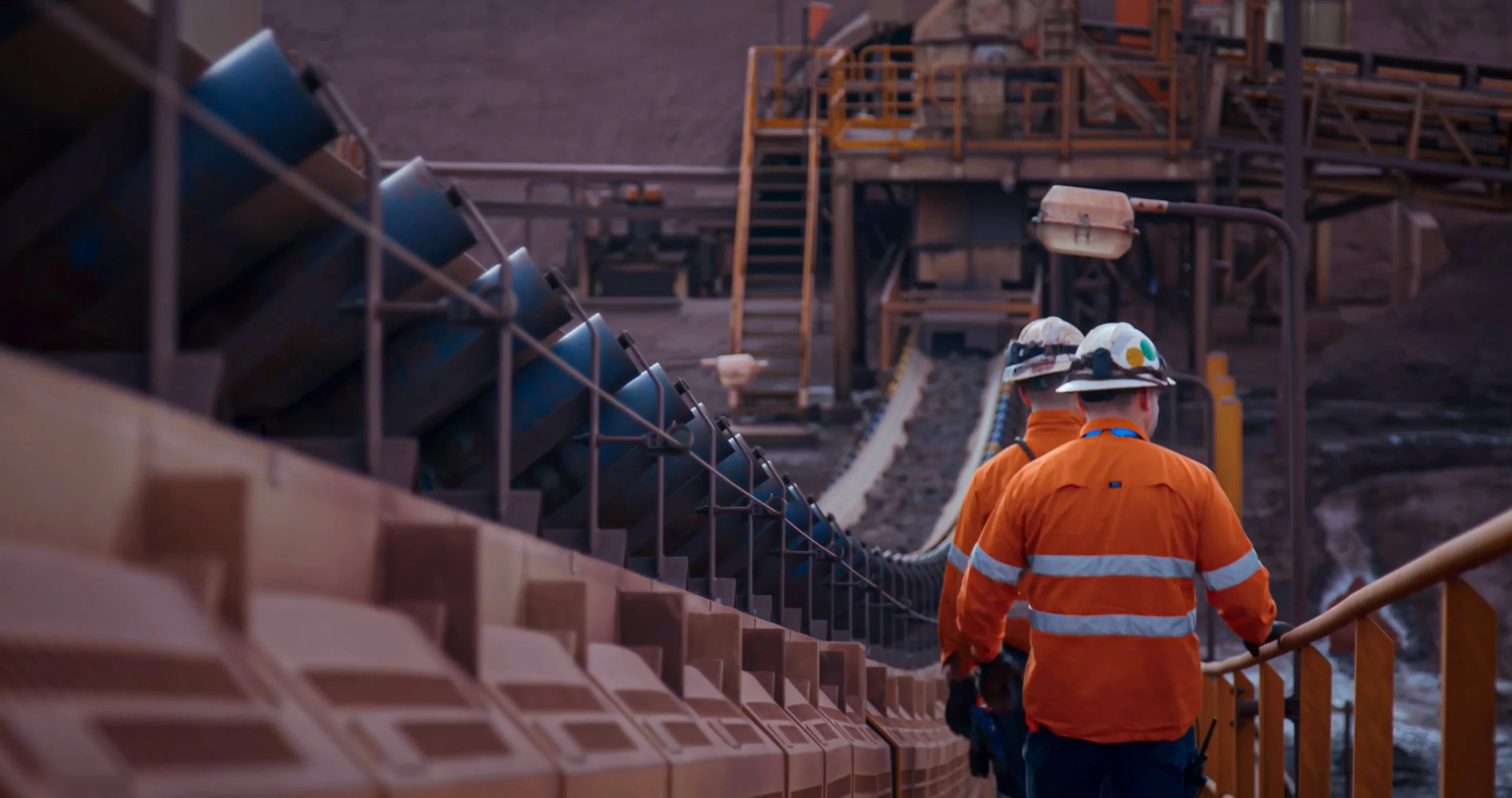 ENERGY&RESOURCES-2025-GLOBAL-Men walking alongside material conveyor belts at a mining site