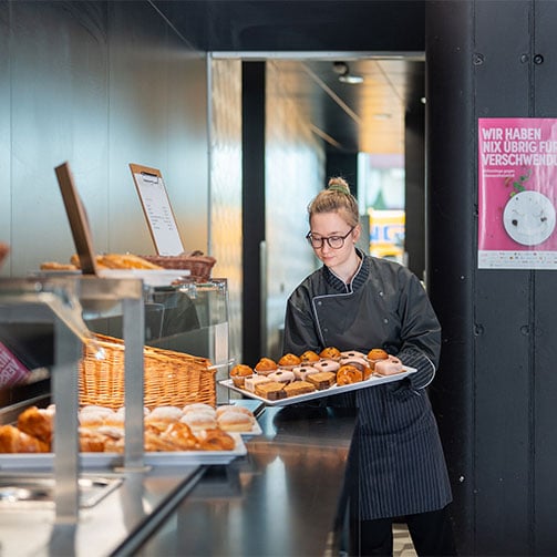 Junge Kuechenhilfe bestueckt das Nachspeisenbuffet.