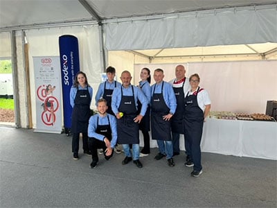 Teammitglieder mit Schuerzen bei Stand von Sodexo bei Event