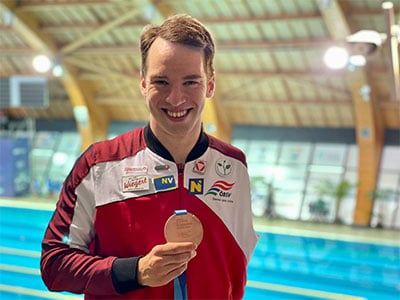 Paraschwimmer Andreas Onea in Sporttrikot zeigt stolz Medaille