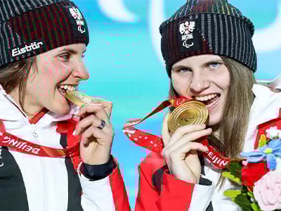 Zwei glueckliche Sportlerinnen mit Sehbehinderung beissen in Goldmedaillen