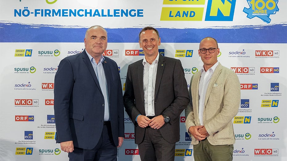 Maenner in Anzuegen vor Fotowand bei NOE Firmenchallenge