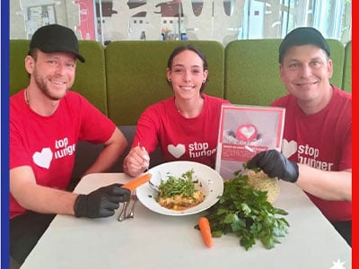 Junge Menschen in Stop Hunger Shirts mit Karotten, Petersilie und Speiseteller