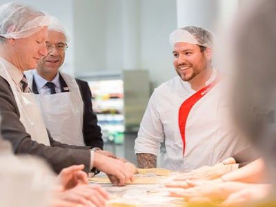verschiedenes Personal beim Ausrollen von Teig