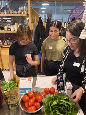 Junge Frauen beim Kochen mit Salat, Tomaten, Basilikum
