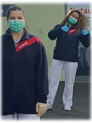 Zwei Mitarbeiterinnen mit Mund-Nasen-Schutz und Handschuhen