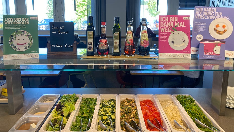 Salatbuffet in Kantine mit buntem Gemuese und Essig und Oel fuer Marinade