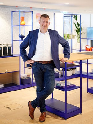 freundlicher Mann in modernem Buero vor Stehtisch