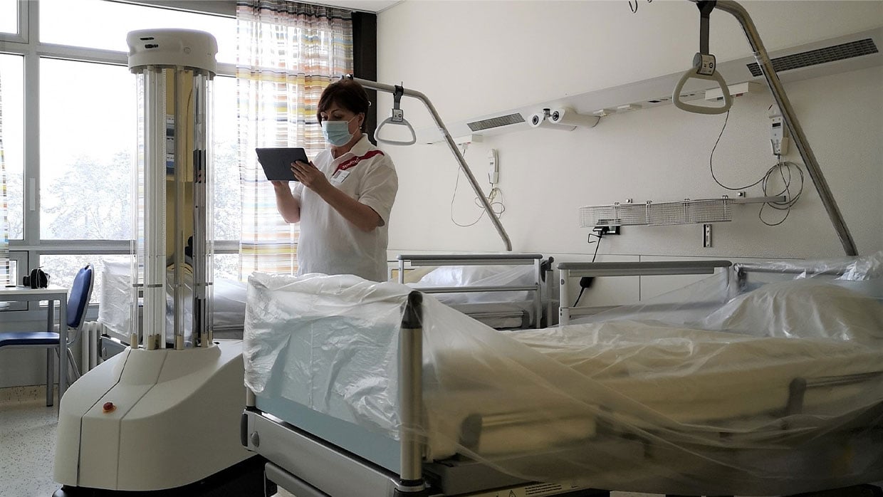 Kompetente Mitarbeiterin in Krankenzimmer bedient Maschine ueber Tablet