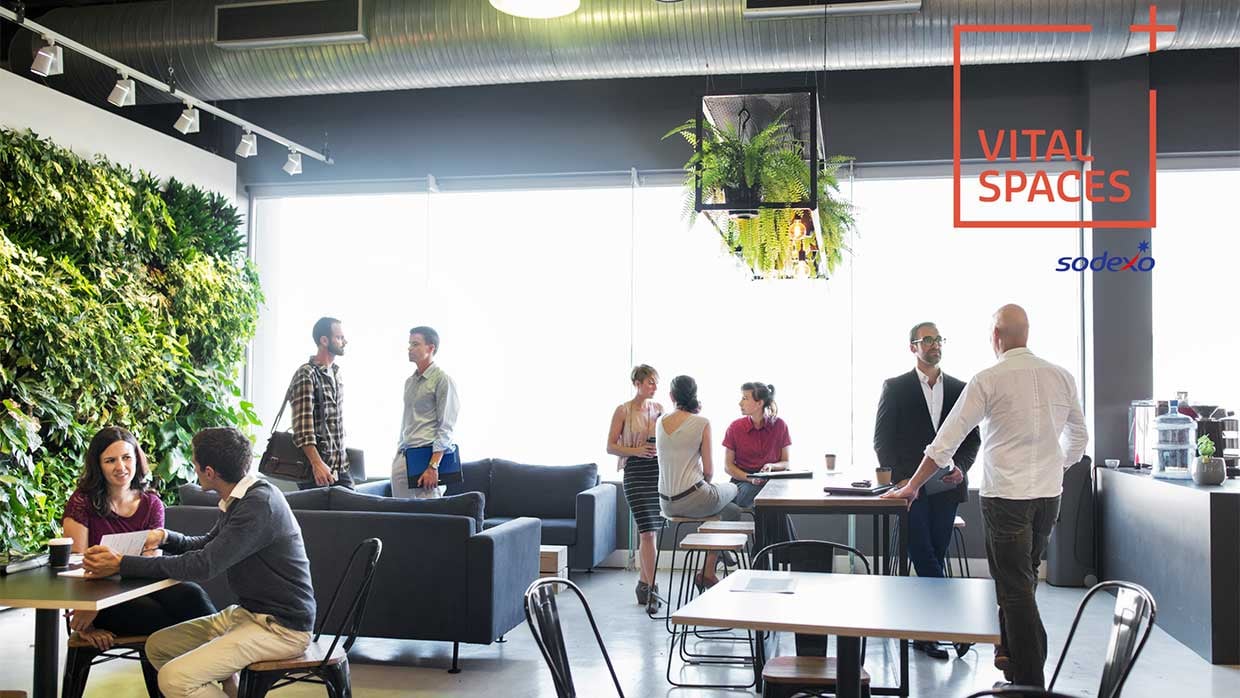 Bild Pressemitteilung Vital Spaces Szene eines modernen Aufenthaltsraumes mit Kaffeebar. Leute stehen da und unterhalten sich.