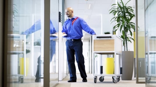 Sodexo Post Mitarbeitender verteilt die Post welche auf einem Wagen verstaut ist