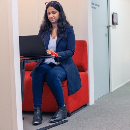 Sodexo Mitarbeitende arbeitet in einem Boot im Büro am Laptop und fühlt sich in der Umgebung sicher und gesund