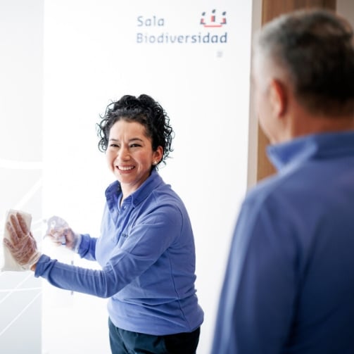 Sodexo Mitarbeitende reinigt ein Fenster und unterhält sich mit ihrem Mitarbeiter 